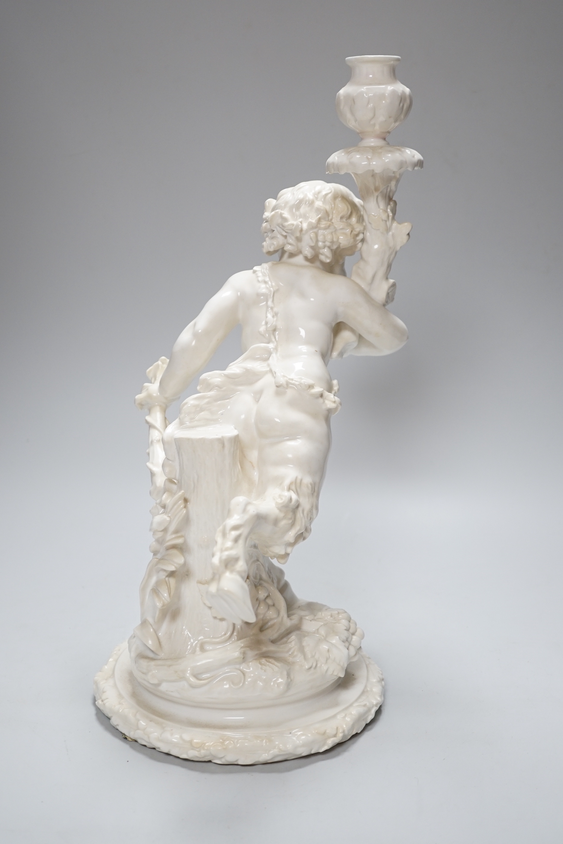 An English white glazed porcelain Bacchanalian fawn candlestick, possibly Moore Brothers, 39cm high
